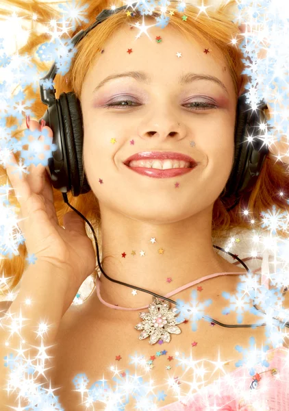 Mosolygó vöröshajú hallgat zenét a hópelyhek a Karácsony-kép — Stock Fotó