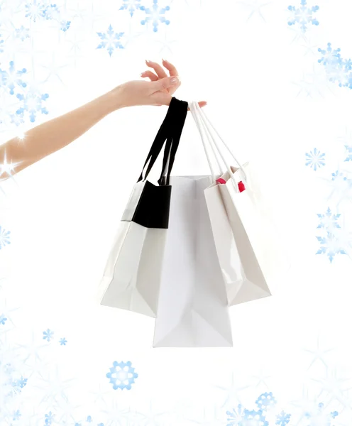 Mano con bolsas de compras y copos de nieve —  Fotos de Stock