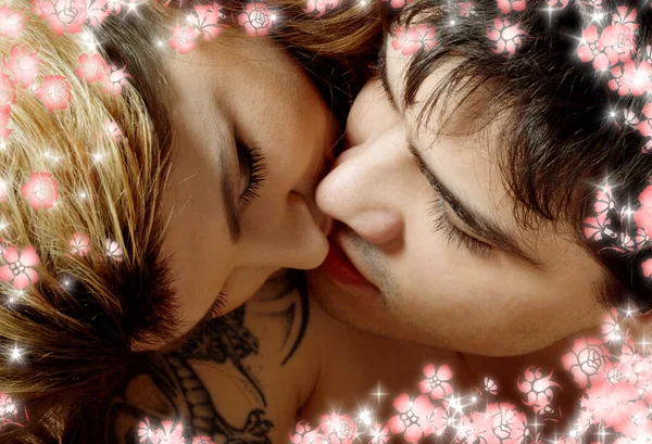 Kissing in bed with flowers — Stock Photo, Image