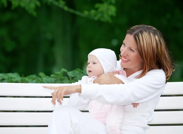 Šťastná matka s dítětem na lavičce — Stock fotografie