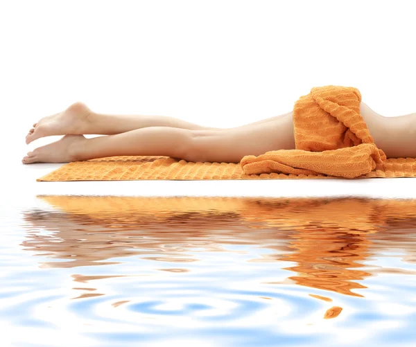 Pernas longas de senhora relaxada com toalha de laranja na areia branca — Fotografia de Stock