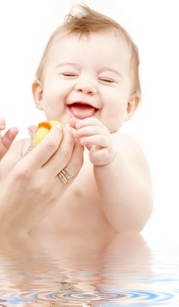 Laughing baby boy in water playing with rubber duck — Stock Photo, Image