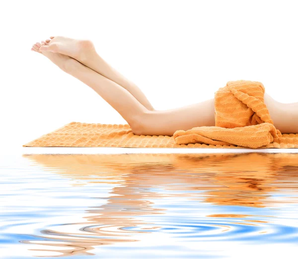 Длинные ноги расслабленной дамы с оранжевым полотенцем — стоковое фото