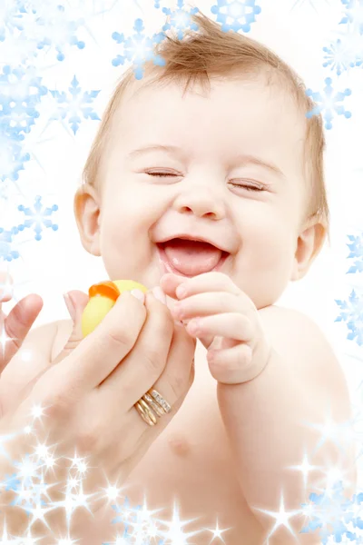 Skrattande pojke i mor händer med gummi anka — Stockfoto