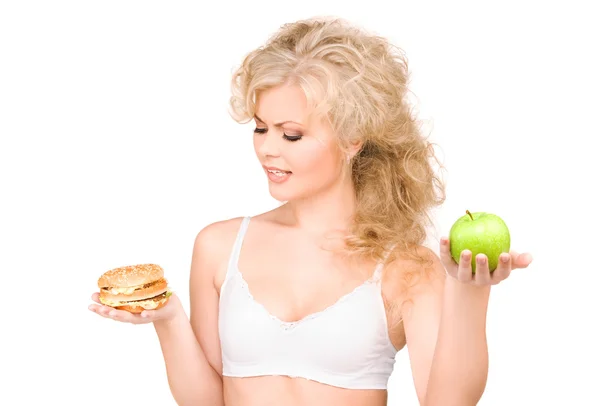 Kadın Burger ve apple arasında seçim yapma Stok Fotoğraf