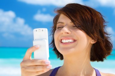 Happy woman with phone on the beach clipart