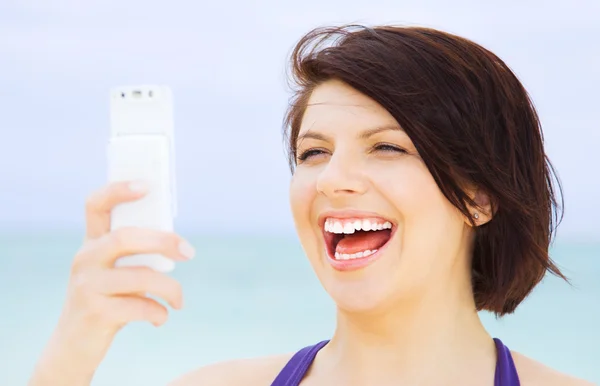 ผู้หญิงมีความสุขกับโทรศัพท์บนชายหาด — ภาพถ่ายสต็อก