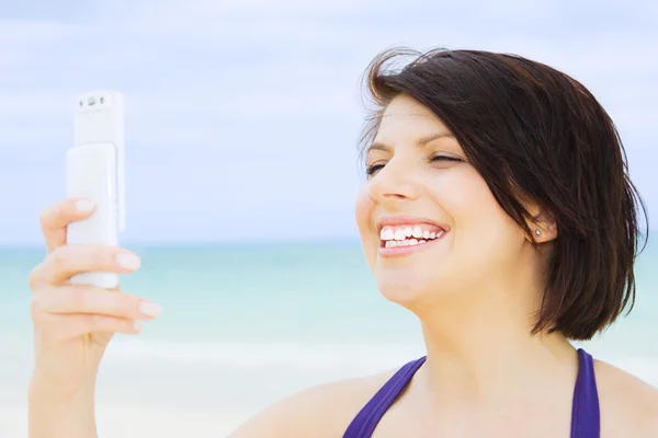 Gelukkige vrouw met telefoon op het strand — Stockfoto