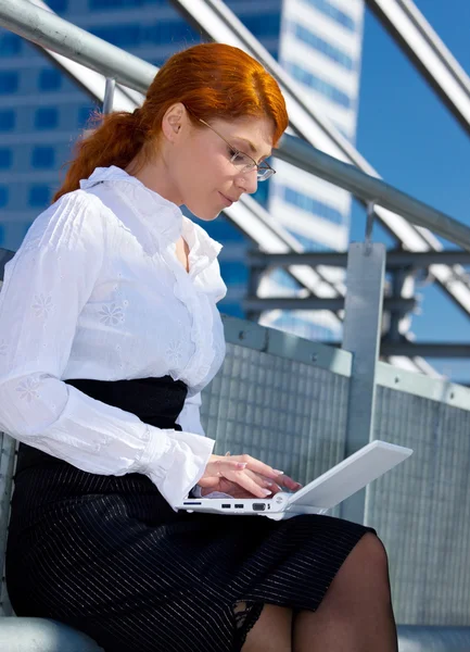 Счастливая деловая женщина с ноутбуком в городе — стоковое фото