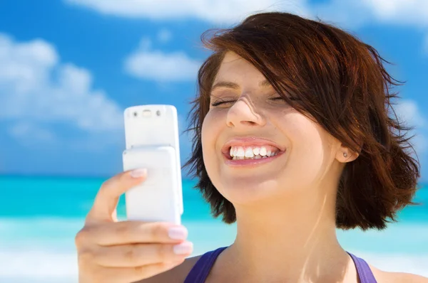 Šťastná žena s telefonem na pláži — Stock fotografie
