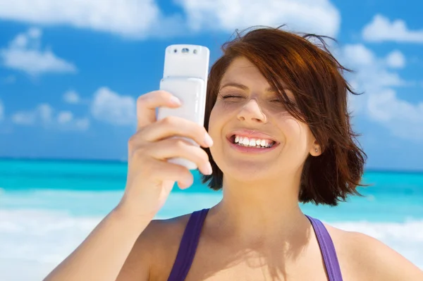 Happy woman with phone on the beach — Zdjęcie stockowe