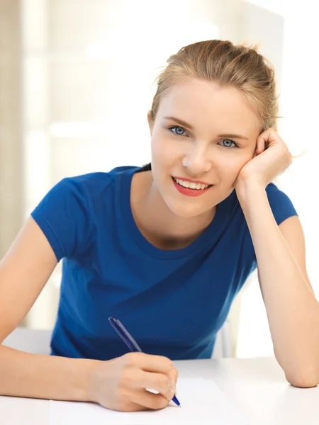 Счастливая девочка-подросток с ручкой и бумагой — стоковое фото