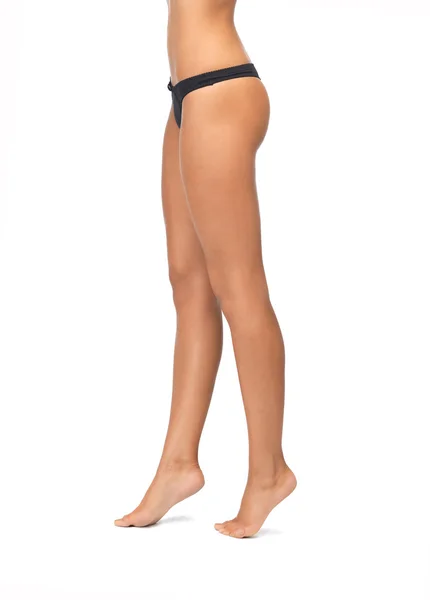 Kvinnliga ben i svart bikini trosor — Stockfoto