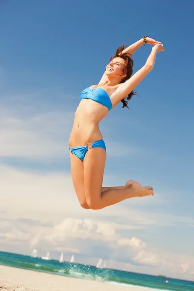 Счастливая прыгучая женщина на пляже — стоковое фото