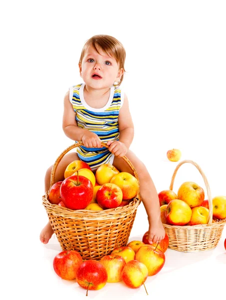 Baby sitting on the basket with apples — Stock Photo, Image