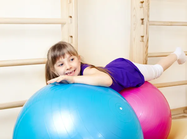 Menina deitada em grandes bolas de ginástica — Fotografia de Stock