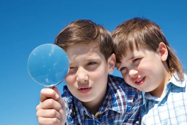 Siblings with magnifying glass — Stock Photo, Image