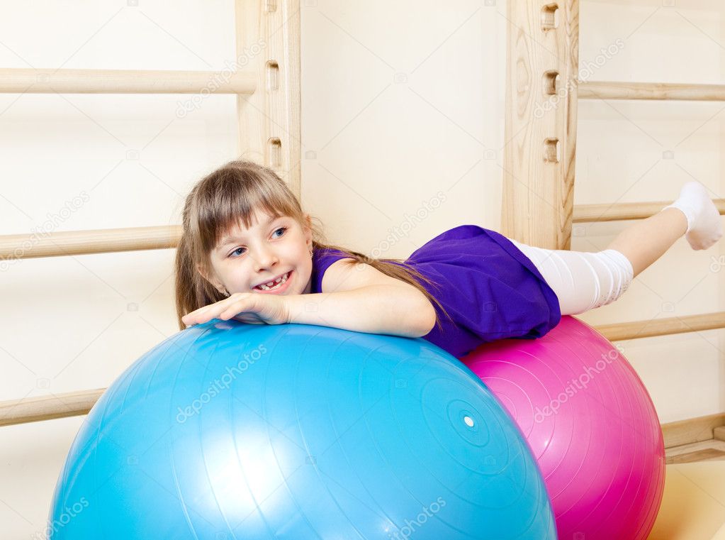 Girl lying on large gymnastic balls