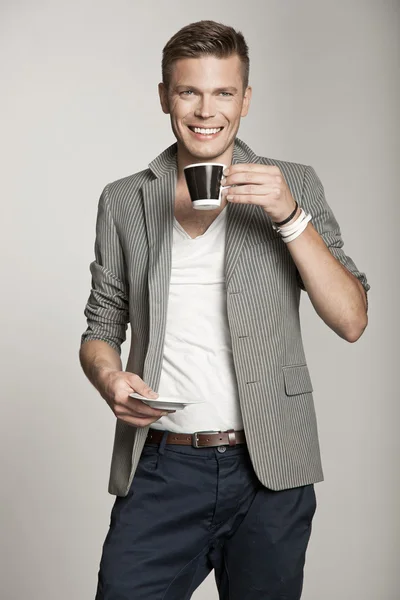 Χαμογελαστός νεαρός άνδρας κρατά φλιτζάνι τσάι — Φωτογραφία Αρχείου
