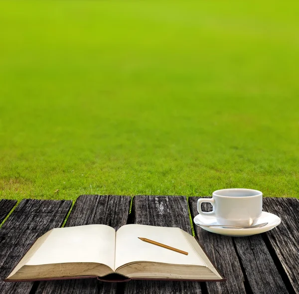 Skriva på Obs boken och dricka varmt kaffe på trädgård — Stockfoto
