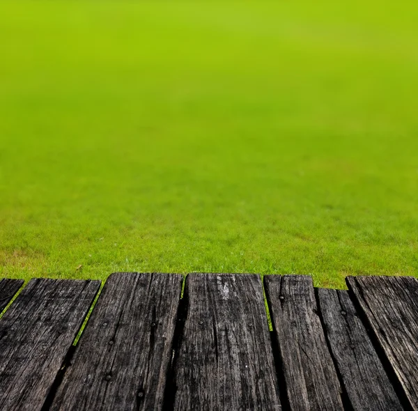 Grunge wooden table with nice grass field background — Stock Photo, Image