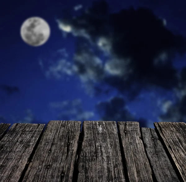 Grunge wooden table with moon in night sky background — Stock Photo, Image