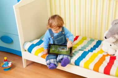 Kid playing with tablet pc clipart