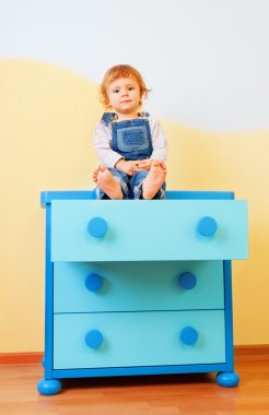 Kid sitting on the cabinet clipart