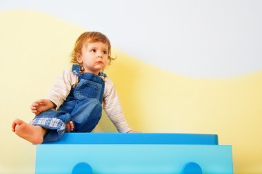 Happy kid sitting on the furniture clipart