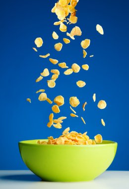 Corn flakes falling to the bowl for breakfast clipart
