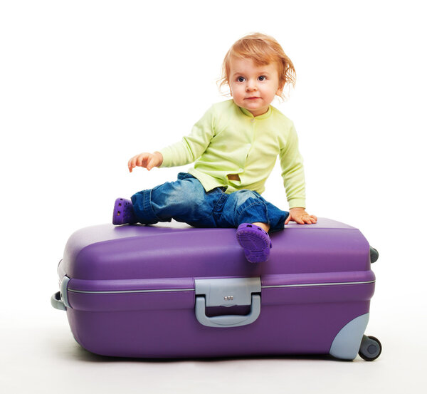 Мальчик сидит на большом чемодане
