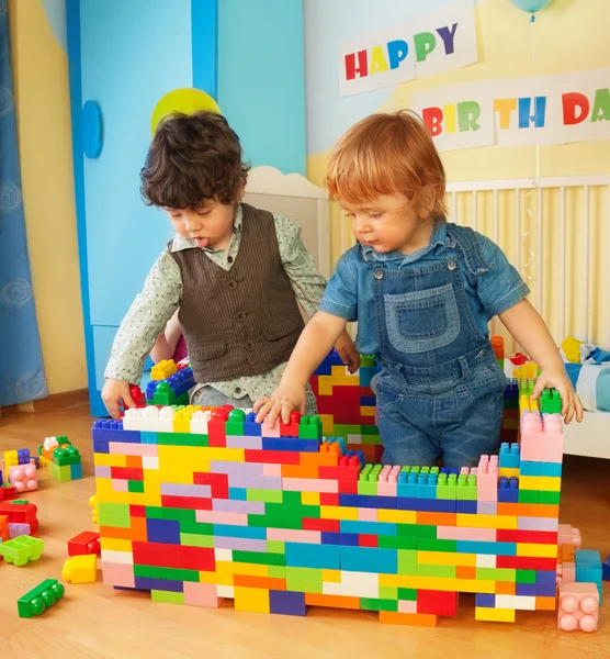 Kinder bauen eine Mauer aus Plastikklötzen — Stockfoto