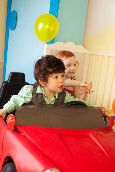 Chico y chica conducir juguete coche — Foto de Stock