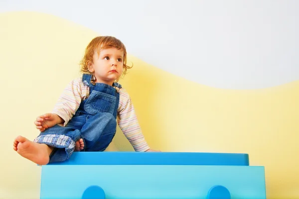 Glückliches Kind auf den Möbeln sitzend — Stockfoto