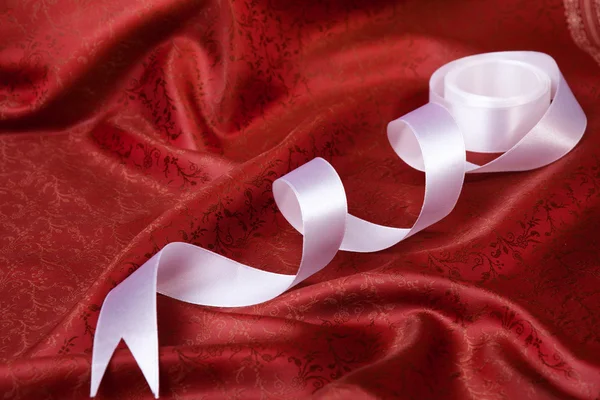Біла стрічка на червоній драпіровці — стокове фото