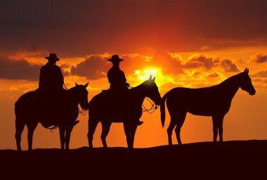 Cowboys and horses under sunset clipart