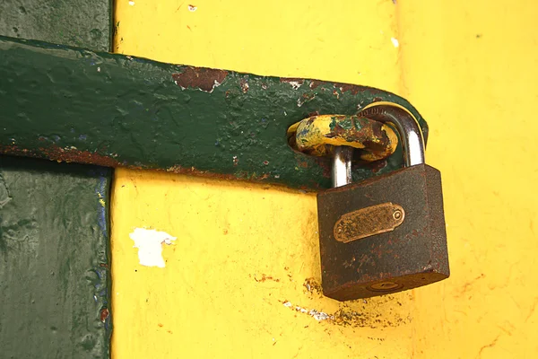 노란색 벽에 오래 된 녹슨된 자물쇠 — 스톡 사진