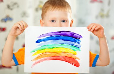 Boy with painted rainbow on paper clipart
