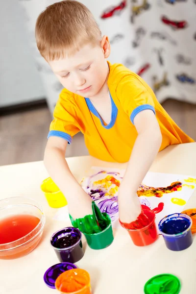 Boy finger paints on paper — Stock Photo, Image
