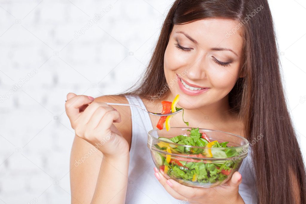 Beautiful brunette woman eating salad