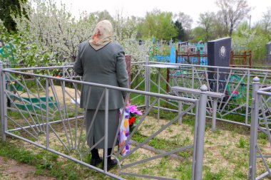 An elderly woman at the grave of her husband clipart