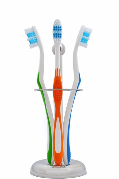 Toothbrushes in a steel holder over white background — Stock Photo, Image