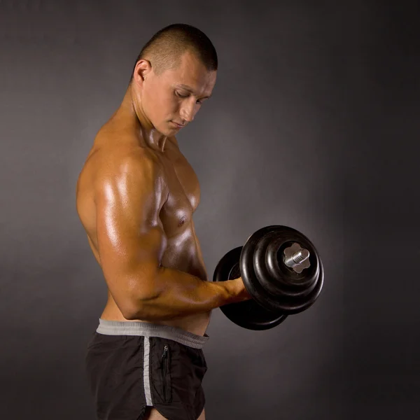 Musculado masculino fisiculturista dumbbell swing — Fotografia de Stock