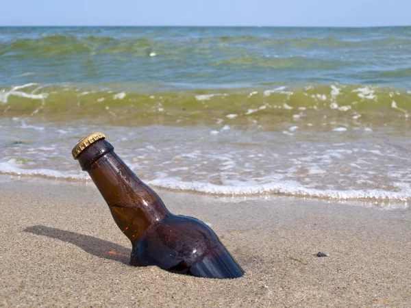 A garrafa de cerveja está enterrada na areia. — Fotografia de Stock