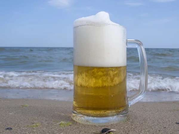 Стекло с пивом на берегу моря — стоковое фото