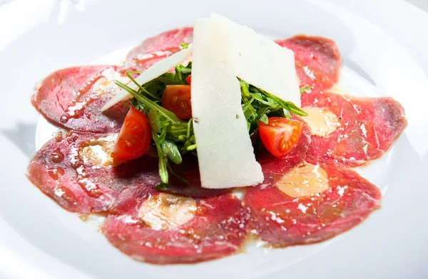 Meat carpaccio with parmesan cheese, tomatoes and herbs — Stock Photo, Image