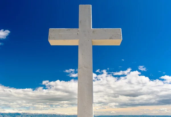 Weißes Kreuz gegen blauen Himmel und flauschige Wolken — Stockfoto