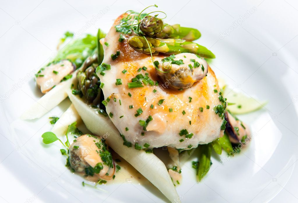 Delicious dish with fish fillet, asparagus and herbs on a plate