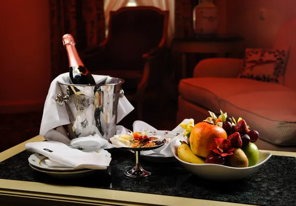 Romantische avond met fles champagne, snoep en vruchten in — Stockfoto