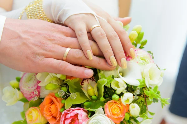 Wedding bouquet and hands of the bride and groom — Stock Photo, Image